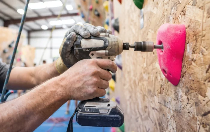 A professional installer setting up a climbing wall in a gym