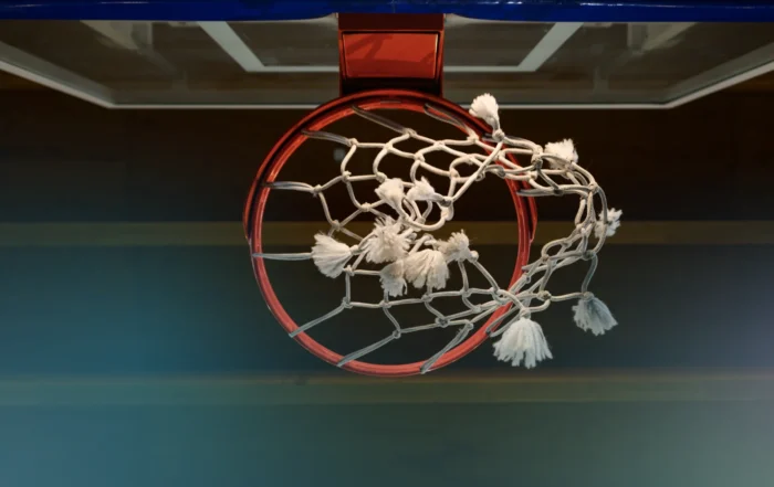 Basketball goal safety straps securing a gymnasium hoop in a large sports facility.