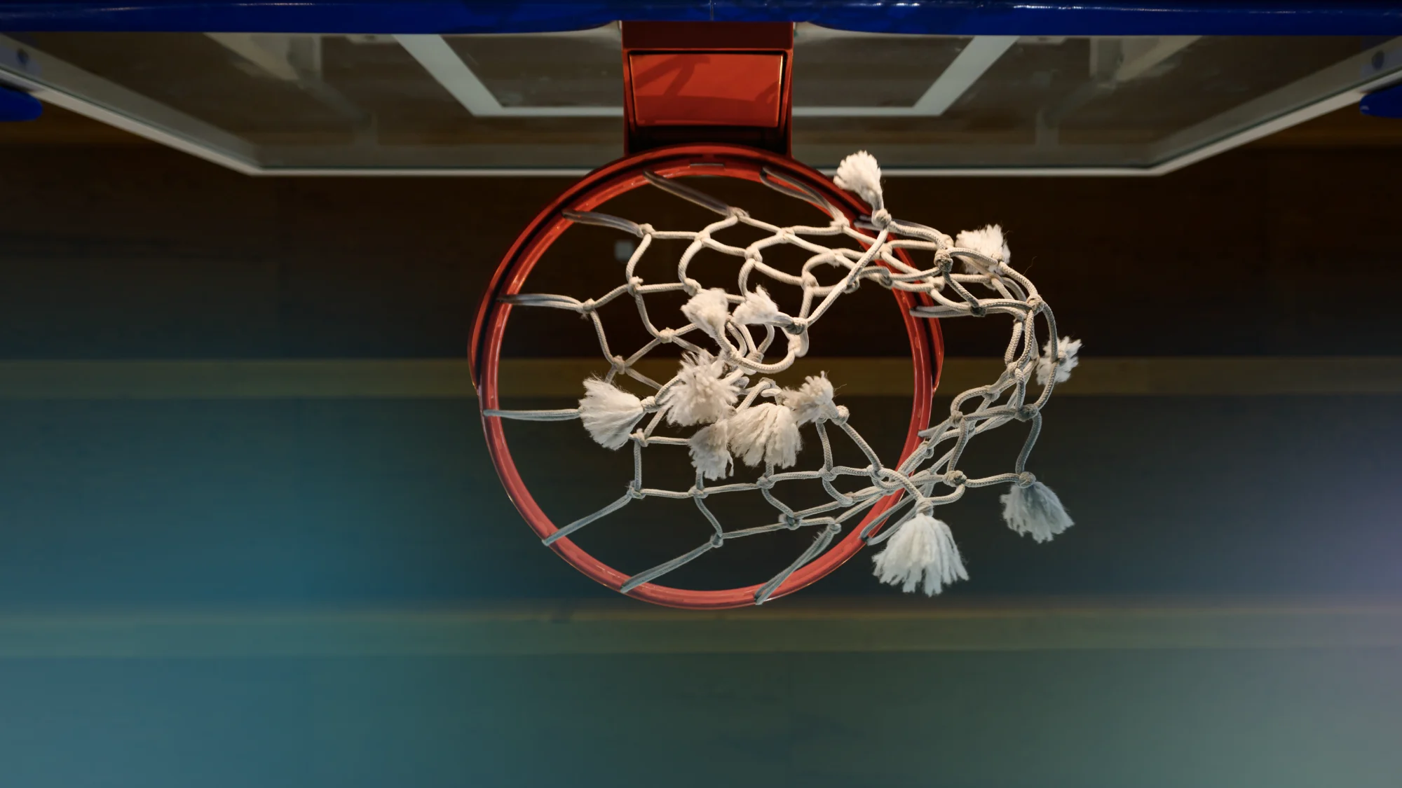 Basketball goal safety straps securing a gymnasium hoop in a large sports facility.